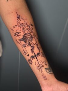 Black and grey tattoo of planets and celestial symbols on forearm — 1920 Tattooz Hub, Ahmedabad