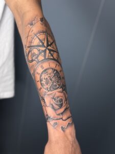 Black and grey tattoo of a compass, pocket watch, and rose on forearm — 1920 Tattooz Hub, Ahmedabad