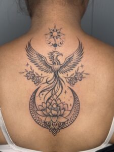 Black and grey tattoo of a phoenix rising above a lotus mandala on upper back — 1920 Tattooz Hub, Ahmedabad