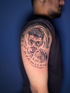 Black and grey tattoo of a man's portrait with lettering on shoulder — 1920 Tattooz Hub, Ahmedabad