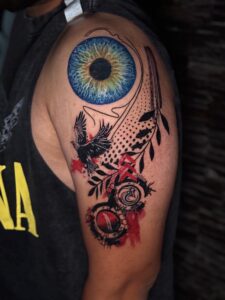 Colored tattoo of a realistic eye with a raven on upper arm — 1920 Tattooz Hub, Ahmedabad