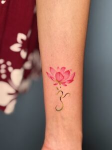 Colored tattoo of a lotus flower with a curved stem on forearm — 1920 Tattooz Hub, Ahmedabad