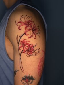 Colored tattoo of two red spider lilies on upper arm — 1920 Tattooz Hub, Ahmedabad