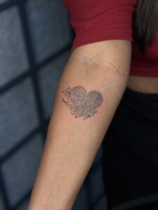 Fine line tattoo of a fingerprint heart with a lily and memorial years on forearm — 1920 Tattooz Hub, Ahmedabad