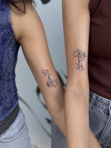 Fine line tattoo of matching koi fish with sun and moon accents on forearm — 1920 Tattooz Hub, Ahmedabad