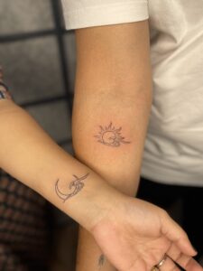 Fine line tattoo of matching sun and moon wave designs on forearm and wrist — 1920 Tattooz Hub, Ahmedabad