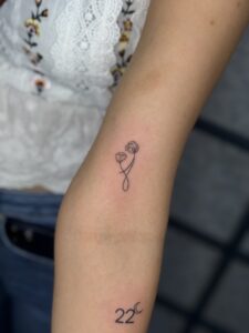 Fine line tattoo of two flowers with a looping stem on forearm — 1920 Tattooz Hub, Ahmedabad