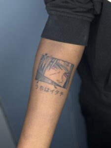 Minimalist tattoo of an anime character portrait with Japanese script on forearm — 1920 Tattooz Hub, Ahmedabad