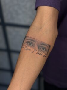 Minimalist tattoo of a pair of eyes with The Eyes I Fell For script on forearm — 1920 Tattooz Hub, Ahmedabad