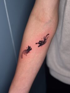 Minimalist tattoo of two black cats on forearm — 1920 Tattooz Hub, Ahmedabad