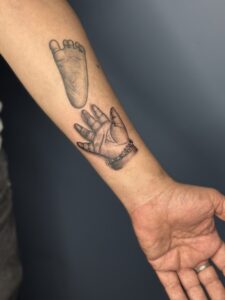 Realistic tattoo of a baby's footprint and handprint on forearm — 1920 Tattooz Hub, Ahmedabad